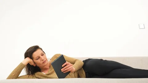 Girl Looking at Tablet Lying on the Couch Stock Footage 85866656
