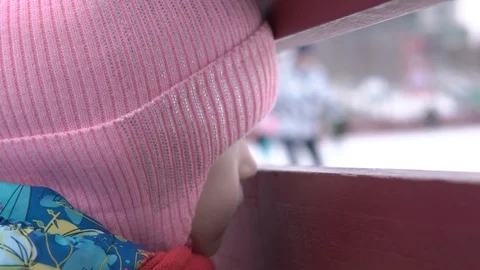 Girl looking through hole between boards on winter day Stock Footage 101752973
