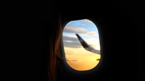 Girl looking through plane window at sunset Stock Footage 159070202