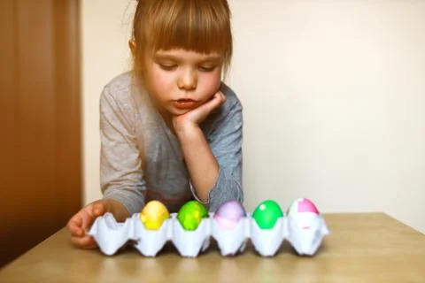 Girl looking at a tray with easter eggs Stock Photos