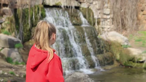 Girl looking at the waterfall view from the back Stock Footage 186557523