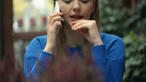 Girl looking worried while talking on cellphone, steadycam shot 스톡 동영상 70434657