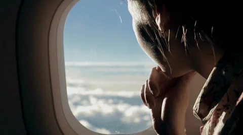 Girl looks at the clouds from airplane window Stock Footage 24867405