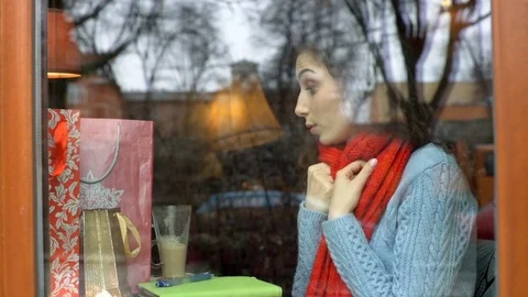 Girl looks cold while sitting by the cafe's window, steadycam shot Stock-Footage 70807155