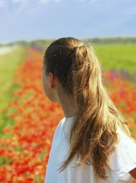 The girl looks into the distance, a blurred floral background. A teenage girl Stock Photos