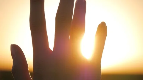 Girl looks at the sun through her hand Stock Footage