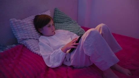 Girl Lying in Bed and Using Smartphone with Pink Neon Lighting Stock Footage 345528356