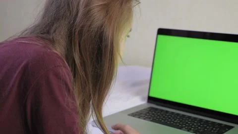A girl is lying on the bed, in front of her is a laptop with a green screen Video stock 201206007