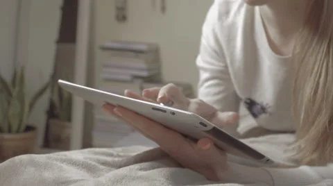 Girl lying on bed at home using tablet. Vidéo 61673434