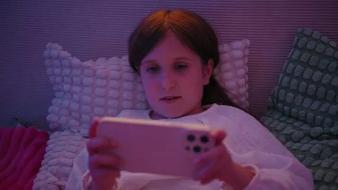 Girl Lying in Bed at Night Watching Smartphone Screen Stock Footage 345528262