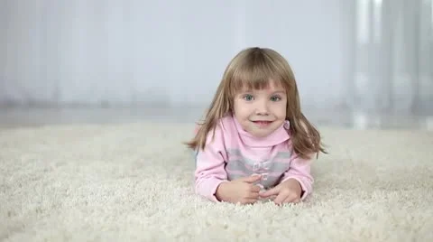 Girl lying on the carpet looking to the camera Stock Footage 8975194