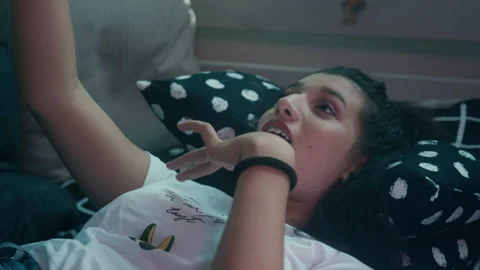 Girl lying down on a bed talking on a smartphone Stock Footage 275011453