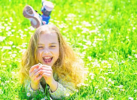 Girl lying on grass, grassplot on background. Child enjoy spring sunny weather Stock Photos