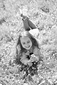 Girl lying on grass, grassplot on background. Child enjoy spring sunny day while Stock Photos