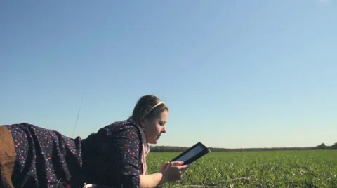 Girl lying on the grass with the tablet. Camera movement with the slider Stock Footage 49816032