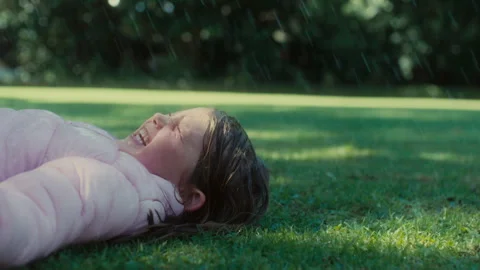 Girl lying on the grass while it's raining Stock Footage 279080565