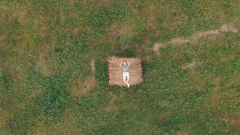 Girl lying on a haystack in a field in summer. Aerial video. Vídeo Stock 120782668