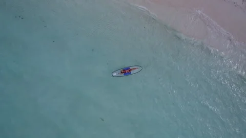 A girl is lying on a paddleboard in the ocean. The camera goes up. Stock Footage 252851031