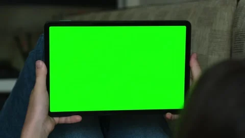 Girl lying on sofa and using digital tech tablet with green screen mock up 库存影片 318546493