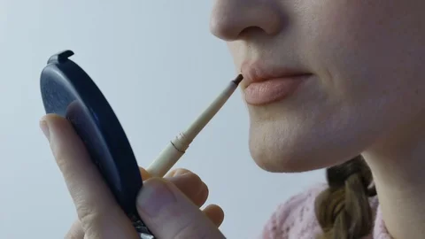 Girl makes a make-up for herself using lipgloss to paint her lips. Face macro Stock Footage 120904532