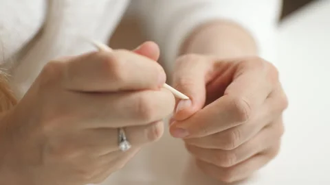 A girl makes a manicure using an orange stick. Treats cuticles. Beauty care Stock Footage 267200448