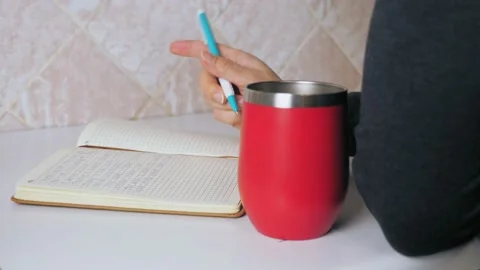 The girl makes a note in a notebook while sitting at the kitchen table and Stock Footage 213225852