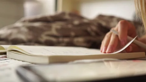 Girl makes notes in a notebook. Hand writes. Girl doing her homework. Remote Stock Footage 135657285