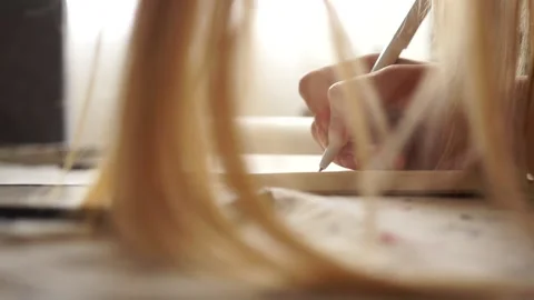 Girl makes notes in a notebook. Hand writes. Girl doing her homework. Remote Stock Footage 135657319