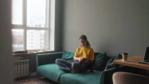 The girl makes notes in a notebook sitting on a bright sofa Stock Footage 166090154