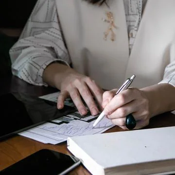 The girl makes notes in a notebook at the table Stock Photos