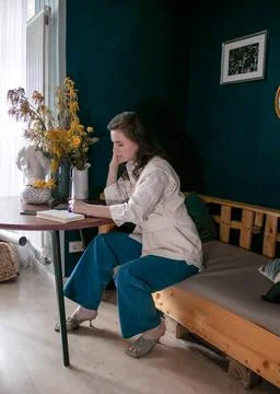 The girl makes notes in a notebook at the table Stock Photos