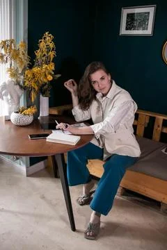 The girl makes notes in a notebook at the table Stock Photos