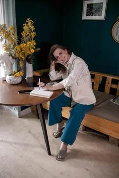 The girl makes notes in a notebook at the table Stock Photos