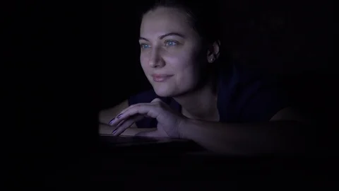 A girl makes an online purchase using a mobile computer while lying on a bed at Video stock 100723404
