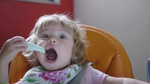 Girl making funny face, playing with fork during feeding time Stock Footage 143292689