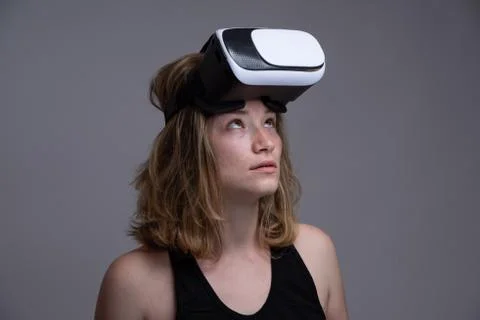 Girl making funny faces while holding on her head a 3D VR wearable gadget Stock Photos