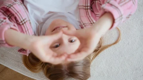 Girl making heart gesture while lying on floor Stock Footage 311918873