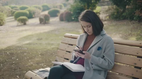 Girl making notes in the park 1 Stock Footage 99206134
