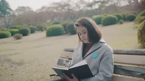 Girl making notes in the park 2 Stock Footage 99206236