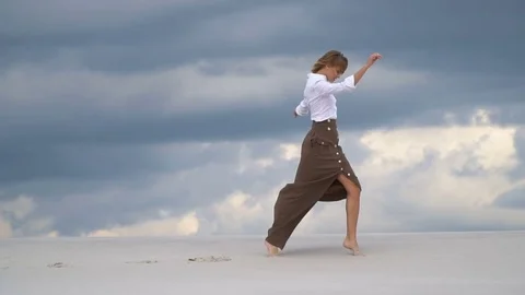 The girl is making a step over the sand against the background of the clouds Stock Footage 76285992