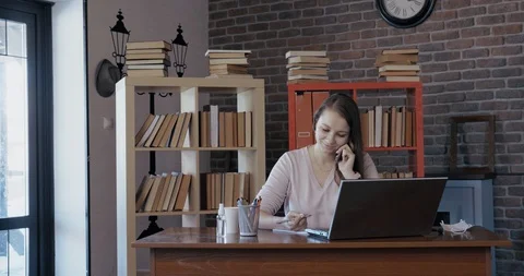 Girl manager at work in office, talking on phone, writes thoughts on paper Stock Footage 128958433