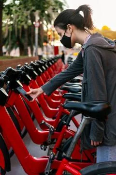Girl with mask scanning the code to unlock a bike Stock Photos
