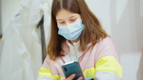 Girl in mask using smartphone in queue to dressing room Stock Footage 151714340
