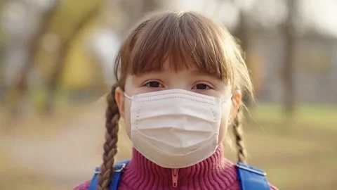 Girl medical mask with backpack smiles, small schoolboy kid protected from covid Stock Footage