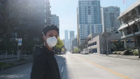 Girl in medical mask crossing empty city street Stock Footage