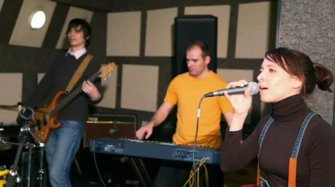 Girl with microphone singing in studio, musicians against Stock Footage