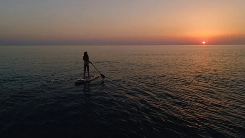 Girl model in bikini rowing  paddle glanders board on open sea sunset Aerial 4k  Stock Footage 122018734