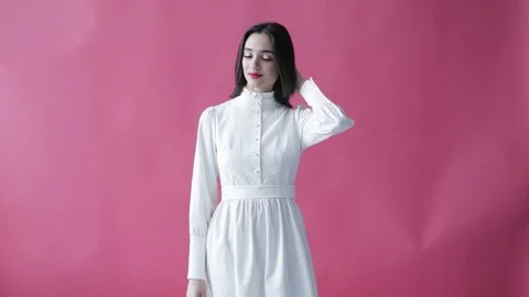 Girl model posing and smiling on a red background. A beautiful woman in a white Stock-Footage 103831876