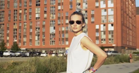 Girl Model Posing For Camera. Sunglasses. Stands on District Street at Sunset Stock Footage 136716375
