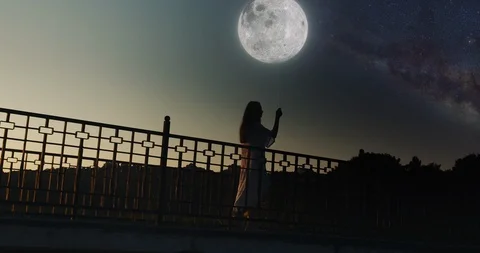 Girl with the moon on a string walking from a sunset to a starry night. Stock Footage 115026984